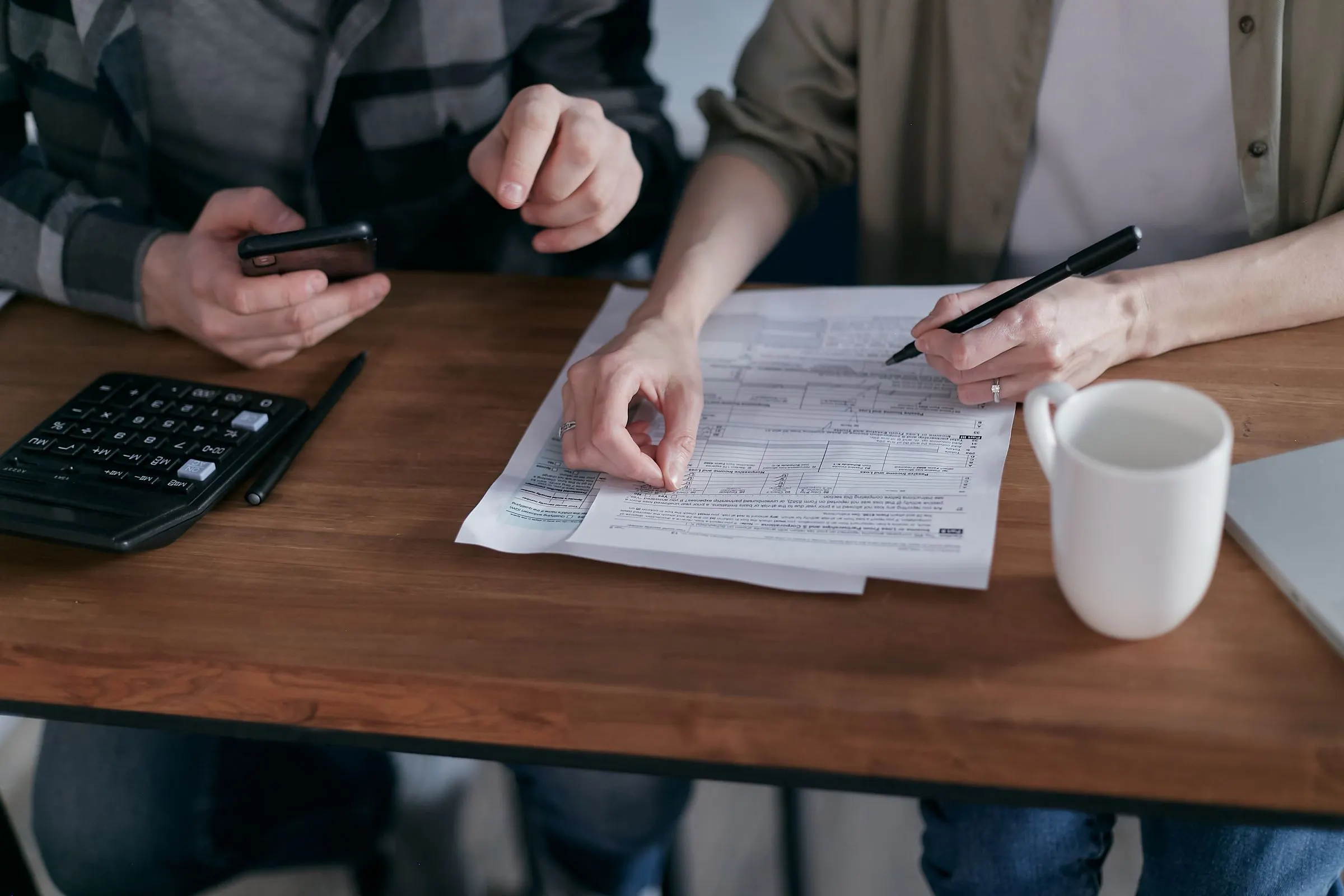 Paar organisiert zu Hause die Finanzen mit Taschenrechner, Smartphone und Unterlagen